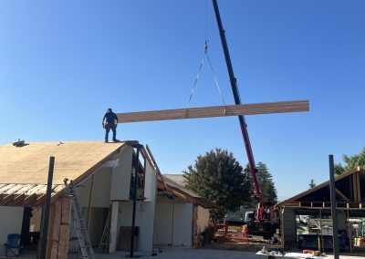 Crane lifting large beam at commercial construction site — Kern County general contractor