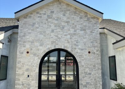 Stone facade exterior with arched black frame window — luxury home construction Bakersfield