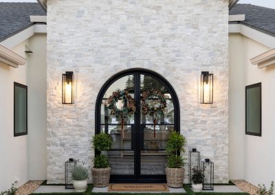Custom stone facade with arched steel entry doors — luxury home remodel Bakersfield CA