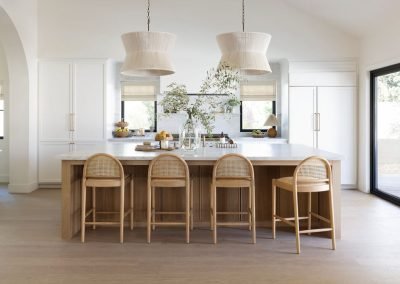 Custom kitchen remodel with marble island, white shaker cabinets, and cane counter stools — Bakersfield CA