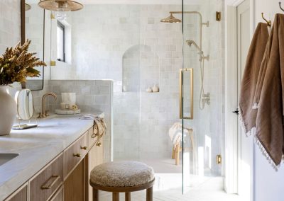 Zellige tile primary bathroom with arched niche, brass fixtures, and fluted oak vanity — custom home remodel Bakersfield CA