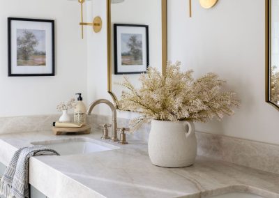Double vanity bathroom with marble countertops, sage green cabinets, and brass mirrors — custom home remodel Bakersfield CA